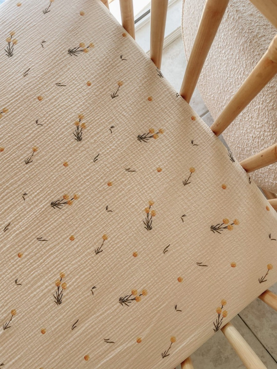 The Softest GOTS Organic certified baby cott sheets with a vintage scandi design and Asutralian yellow billy button flowers on a neutral background