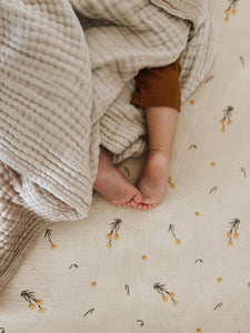 The Softest GOTS Organic certified baby bassinet sheets with a vintage scandi design and Asutralian yellow billy button flowers on a neutral background