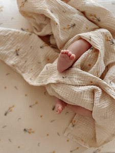 The Softest GOTS Organic certified baby bassinet sheets with a vintage scandi design and Asutralian yellow billy button flowers on a neutral background