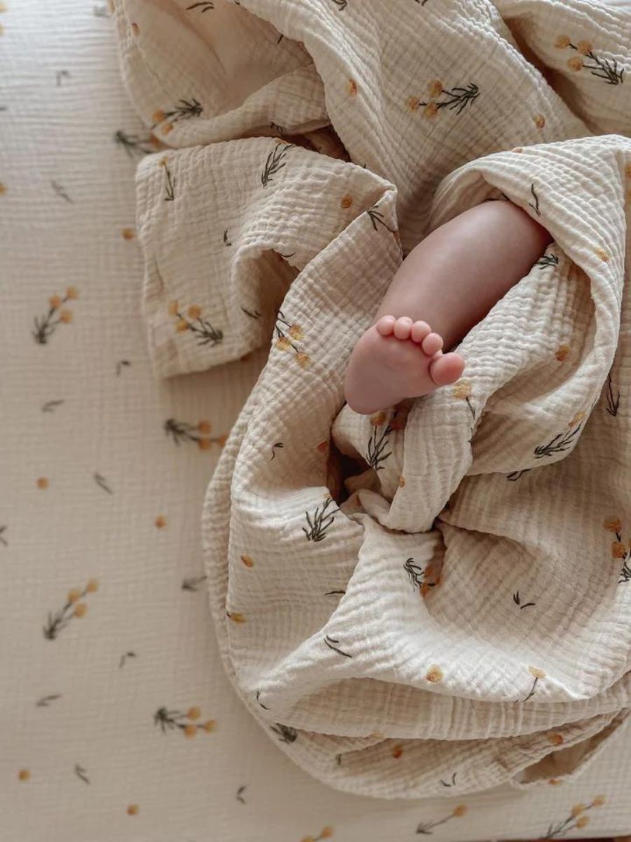 The Softest GOTS Organic certified baby bassinet sheets with a vintage scandi design and Asutralian yellow billy button flowers on a neutral background