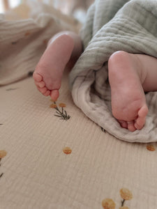 The Softest GOTS Organic certified baby bassinet sheets with a vintage scandi design and Asutralian yellow billy button flowers on a neutral background