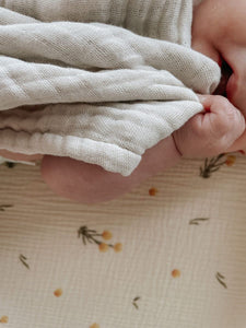 The Softest GOTS Organic certified baby bassinet sheets with a vintage scandi design and Asutralian yellow billy button flowers on a neutral background