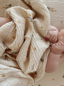 The Softest GOTS Organic certified baby bassinet sheets with a vintage scandi design and Asutralian yellow billy button flowers on a neutral background